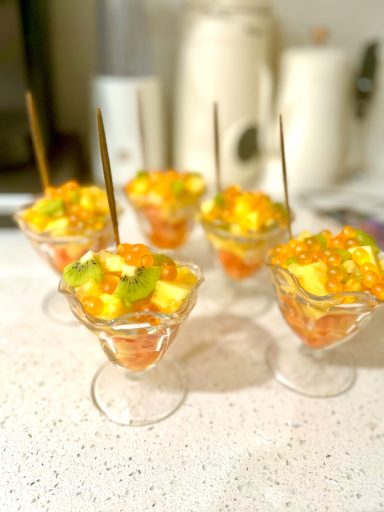 Colorful fruit cups with mango, pineapple, and corn topped with mint leaves.