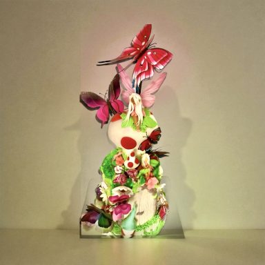 Colorful sculpture of a figure adorned with flowers and butterflies.