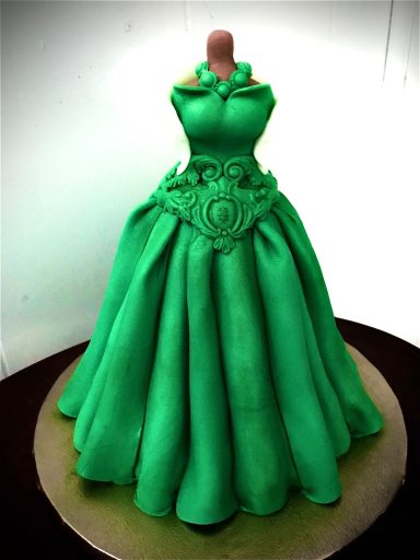 Green gown cake designed like a formal dress with intricate detailing.