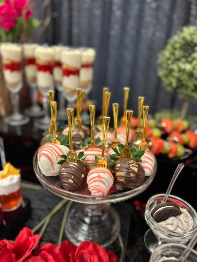 A dessert display featuring chocolate-covered strawberries and decorative glasses.
