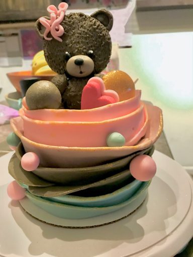 A whimsical dessert featuring a teddy bear on colorful layered plates with sweets.