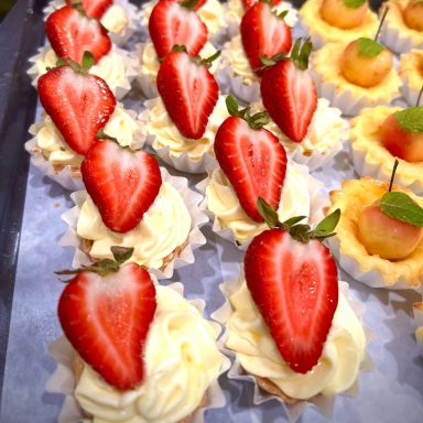 Mini cupcakes topped with whipped cream and fresh strawberries.
