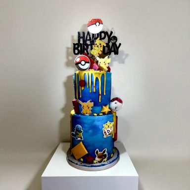 A colorful Pokémon-themed birthday cake with decorations and a "Happy Birthday" topper.