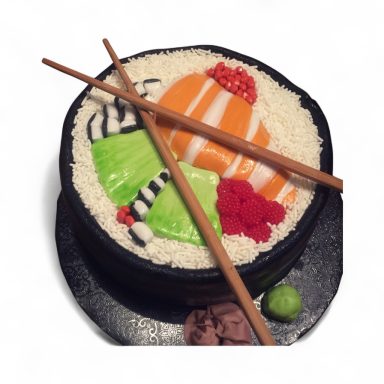 A round cake designed to resemble sushi with colorful toppings and chopsticks.