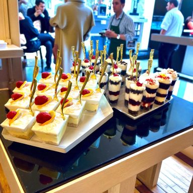 Two dessert platters with various layered parfaits and cakes topped with fruit and gold accents.