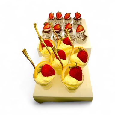 Dessert display with layered cakes and strawberry-topped parfaits on a white background.