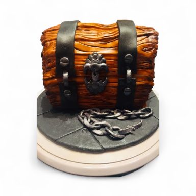 Brown treasure chest cake with black straps and a chain detail on a round base.