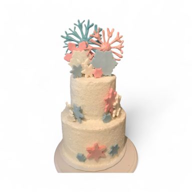 A two-tiered cake adorned with colorful coral and starfish decorations.