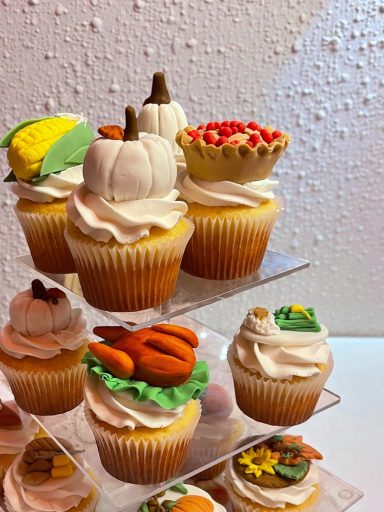 Colorful cupcakes decorated with autumn themes, including pumpkins and carrots.
