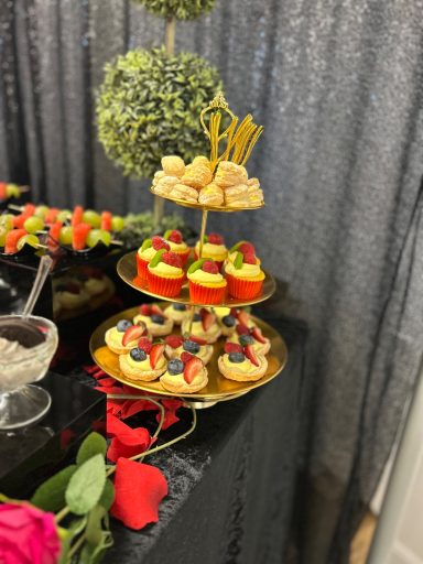 A tiered dessert stand featuring mini cakes and decorated cupcakes with strawberries.