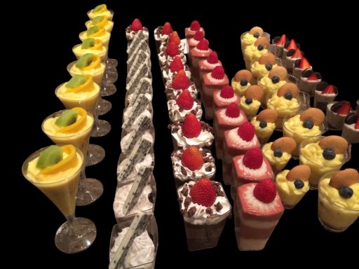 A variety of colorful desserts including parfaits, cakes, and cupcakes arranged in rows.