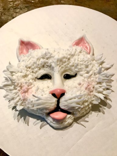 Cat face cake decorated with white frosting and pink accents.